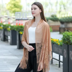 Close-up of elegant lace shawl with floral pattern and tassels worn by a model