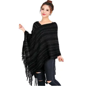 Primer plano de un elegante poncho de punto negro con borlas en una modelo