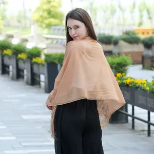 Elegant champagne lace shawl with floral fringe detail shown on model in outdoor park