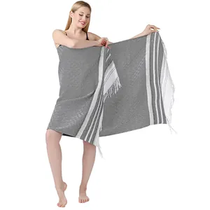 Toalla de playa turca grande de algodón gris con flecos lucida por modelo