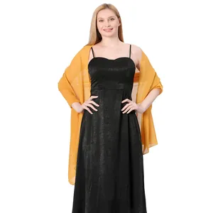 Detailed view of long yellow chiffon shawl draped over a elegant black evening dress