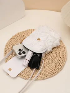 Detalle de bolso bandolera blanco con flores mostrando su amplia capacidad para objetos.