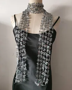 Detail of silver snowflake sequin scarf worn on a black satin dress.