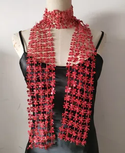 Close-up detail of a red sequined flower-pattern scarf worn on a black satin slip dress.