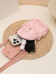 Vista detallada de la textura floral 3D y el interior del bolso bandolera rosa con perlas