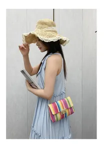 Asiatisches Model mit einer farbenfrohen gewebten Strohumhängetasche mit Goldkette