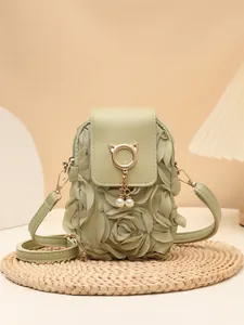Detalle de bolso bandolera verde salvia con pétalos 3D y colgante de gato y perla