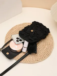 Primer plano de un bolso bandolera negro con flores que muestra su capacidad interna