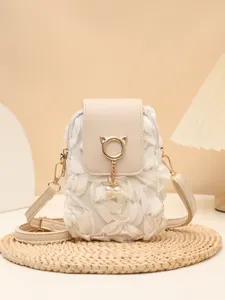 Detalle frontal de bolso bandolera crema con anillo de orejas de gato y perlas