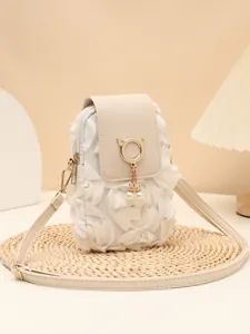 Vista detallada del bolso bandolera crema con pétalos de tela y colgante de gato perla