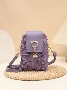 Detalle de bolso bandolera morado con rosas 3D de tela y colgante de gato y perlas.