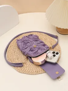 Vista detallada del bolso bandolera morado con textura floral y colgantes de perlas