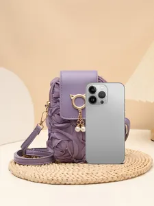 Detalle de bolso bandolera morado con pétalos de rosa y colgante de gato dorado con perla.