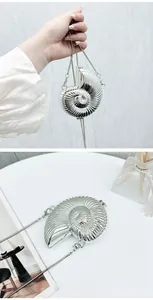 Close-up detail of a silver nautilus shell mini acrylic bag with a sleek metal chain strap