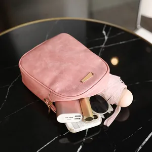 Mini borsa a tracolla in pelle rosa che mostra la capacità su un tavolo di marmo