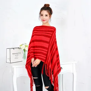 Elegante poncho de punto a rayas rojas con flecos llevado por una modelo en un estudio.