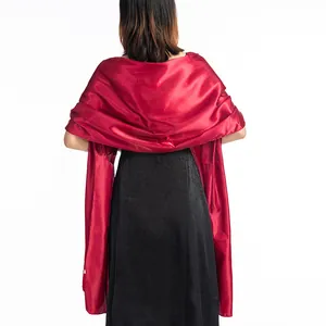 Detail view of an elegant red satin shawl draped over a black formal evening dress for women