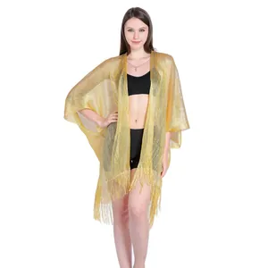 Close-up detail of shimmering gold fringe shawl holiday beach cover-up on a professional model