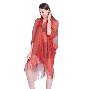 Close-up detail of a red metallic sheer shawl with elegant fringe worn by a model
