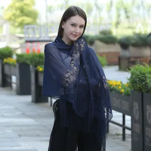 Detail view of navy blue floral lace shawl with elegant tassels worn outdoors