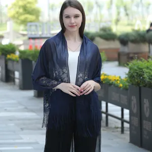 Elegant woman wearing a navy blue lace shawl scarf with fringe details outdoors.
