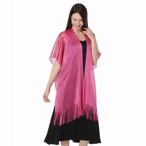 Detailed view of pink metallic shawl with fringe on female model over black dress.