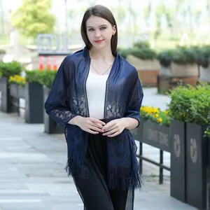 Elegant navy blue lace shawl with delicate fringe tassels shown on a model outdoors