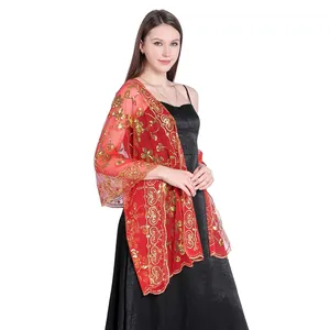 Detailed view of elegant red lace shawl with gold sequins worn over a black formal dress