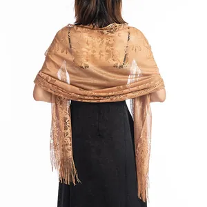 Back view of an elegant gold floral lace shawl with fringe worn over a black dress