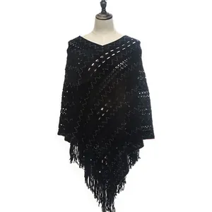 Detailed view of a black knitted crochet poncho with hollow patterns and tassel fringe