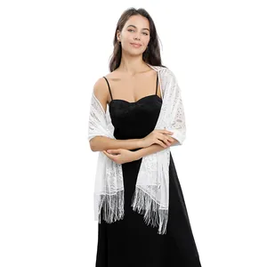 Close-up of white floral lace shawl with fringe tassels draped over black evening dress