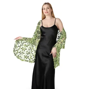 Dettaglio ravvicinato di un elegante scialle in pizzo verde con paillettes e ricami