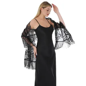 Detail of elegant black mesh shawl with peacock tail sequin embroidery and tassels.