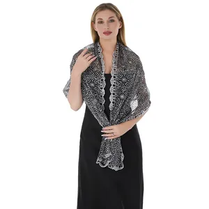 Detail view of an elegant silver lace shawl with floral embroidery on a black dress