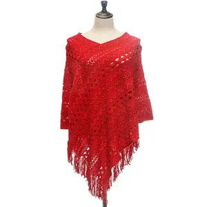 Detailed view of red knitted poncho shawl featuring openwork patterns and tassels.