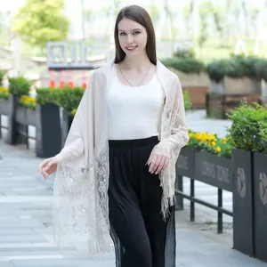 Detailed view of elegant beige lace shawl with floral embroidery and fringes