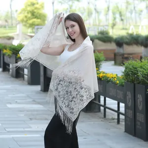 Detailed view of an elegant cream white lace shawl featuring floral embroidery and long fringes