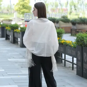 Back view of an elegant white lace shawl featuring delicate tassels and sheer texture.