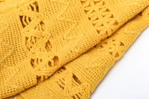 Close-up of yellow knit shawl showing intricate hollow-out patterns and soft texture.