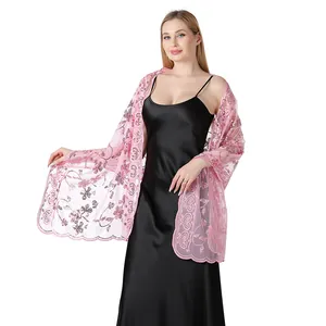 Detail view of pink sequined mesh shawl worn over a black satin evening dress.