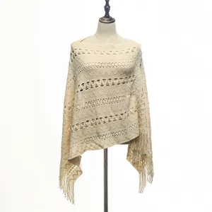 Detailed view of the intricate crochet patterns on a cream knitted poncho with tassels