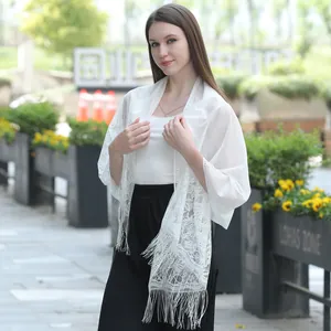 Detailed view of a white floral lace shawl with delicate fringe for evening wear