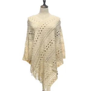 Detail view of cream knitted pullover poncho with hollow-out patterns and tassels