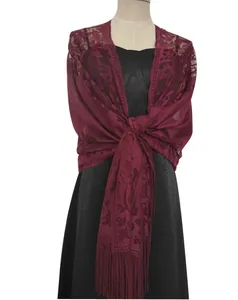 Close-up of elegant burgundy lace shawl with fringe tassels on mannequin.
