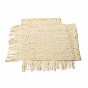 Detailed view of the hollow-out geometric knit pattern and tassels on a beige shawl