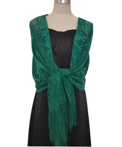 Close-up of elegant green lace shawl with tassels on a black dress mannequin.
