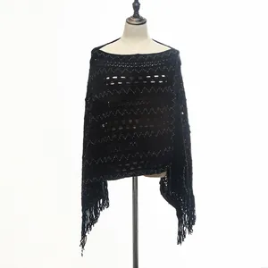Detailed shot of a black knitted loose pullover poncho featuring decorative fringe accents