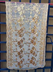 Macro view of gold sequin floral embroidery on a lightweight sheer mesh evening gown shawl