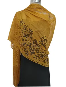 Close-up detail showing the intricate floral hollow-out patterns of a gold lace shawl