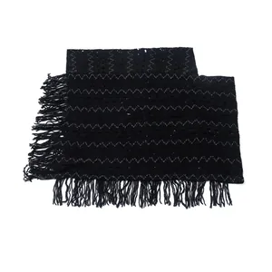 Detailed macro view of black knitted poncho featuring zigzag patterns and stylish fringe